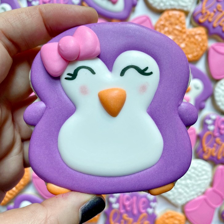 penguin cookies decorated with a bow and royal icing 