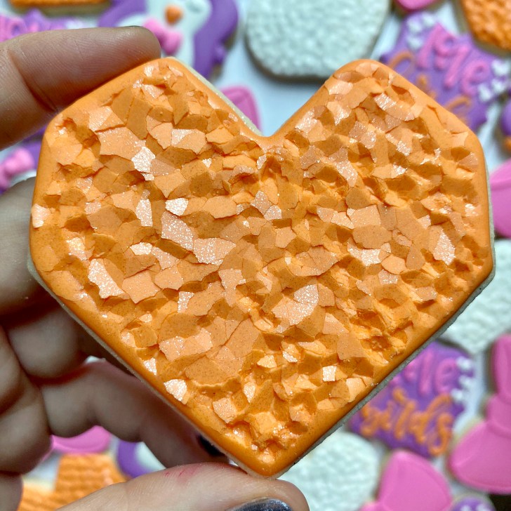 heart cookies decorated with orange royal icing 